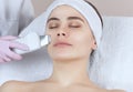 The doctor-cosmetologist makes the apparatus a procedure of ultrasound cleaning of the facial skin of a beautiful, young woman in Royalty Free Stock Photo