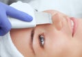 The doctor-cosmetologist makes the apparatus a procedure of ultrasound cleaning of the facial skin