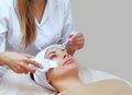 The doctor-cosmetologist makes the apparatus a procedure of ultrasound cleaning of the facial skin of a beautiful, young woman Royalty Free Stock Photo