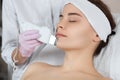 The doctor-cosmetologist makes the apparatus ultrasound cleaning procedure of of the facial skin of a beautiful young woman in a Royalty Free Stock Photo