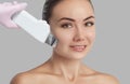The doctor-cosmetologist makes the apparatus ultrasound cleaning procedure of of the facial skin of a beautiful young woman in a Royalty Free Stock Photo