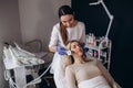 The doctor-cosmetologist makes the Cryotherapy procedure of the facial skin of a beautiful, young woman in a beauty Royalty Free Stock Photo