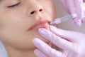 The doctor cosmetologist makes Lip augmentation procedure of a beautiful woman in a beauty salon