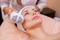 The doctor-cosmetologist makes the procedure Cryotherapy of the facial skin of a beautiful, young woman in a beauty salon