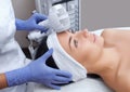 The doctor-cosmetologist makes the procedure Cryotherapy of the facial skin of a beautiful, young woman in a beauty salon. Royalty Free Stock Photo