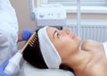 The doctor-cosmetologist makes the procedure Microcurrent therapy On the hair of a beautiful, young woman in a beauty salon.