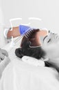 The doctor-cosmetologist makes the procedure Microcurrent therapy On the hair of a beautiful, young woman in a beauty salon. Royalty Free Stock Photo