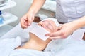 Doctor cosmetologist prepares collagen face mask for female patient