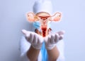 Doctor demonstrating virtual image of infected female reproductive system on light background, closeup. Vaginal candidiasis