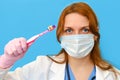 Doctor dentist in a medical mask with a toothbrush in hand on a blue background, portrait