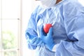 The doctor is describing the heartbeat and heart position on the body. Doctor cardiologist. doctor in surgical clothes holding red