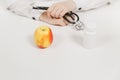 Doctor at desk with bottle white pills, apple in office in hospital. Woman holds in hands stethoscope in consulting room Royalty Free Stock Photo