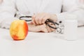 Doctor at desk with bottle white pills, apple in office in hospital. Woman holds in hands stethoscope in consulting room Royalty Free Stock Photo