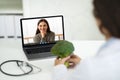 Doctor dietician have online consultation with woman patient, holding broccoli