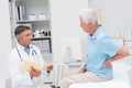 Doctor discussing reports with patient suffering from backache Royalty Free Stock Photo