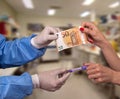 Doctor in disposable gloves sells the vaccine to a female patient for fifty euros. The new vaccine against the Coronavirus