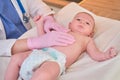 The doctor does gymnastics and massage to a newborn baby. Nurse in uniform doing warm-up exercises to the child Royalty Free Stock Photo