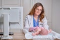 The doctor does gymnastics and massage to a newborn baby. Nurse in uniform doing warm-up exercises to the child Royalty Free Stock Photo