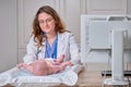 The doctor does gymnastics and massage to a newborn baby. Nurse in uniform doing warm-up exercises to the child Royalty Free Stock Photo