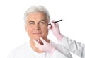 Doctor drawing marks on mature man`s face for cosmetic surgery operation Royalty Free Stock Photo