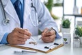 A doctor efficiently completes medical examination documentation and record-keeping by writing on a clipboard using a pen, A