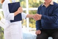 Doctor and elderly patient shaking hands in hospital