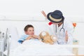 Doctor entertaining sick boy in hospital bed Royalty Free Stock Photo