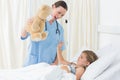 Doctor entertaining sick girl with teddy bear Royalty Free Stock Photo