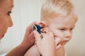 Doctor examines ear with otoscope in a pediatrician room. Royalty Free Stock Photo