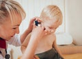 Doctor examines ear with otoscope in a pediatrician room. Royalty Free Stock Photo