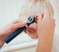 Doctor examines ear with otoscope in a pediatrician room. Royalty Free Stock Photo