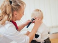 Doctor examines ear with otoscope in a pediatrician room. Royalty Free Stock Photo