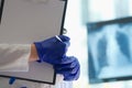 Doctor examines x-ray of lungs and holds clipboard