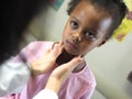 Doctor examining an African-American child`s throat in a hospital