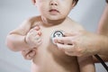 Doctor examining asian baby girl and listen her heart beat