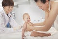 Doctor examining the baby with a stethoscope in the doctors office, mother holding the baby Royalty Free Stock Photo