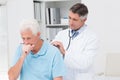 Doctor examining coughing senior patient Royalty Free Stock Photo