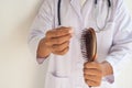 The doctor is examining the hair brush to prove hair loss.