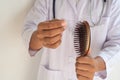 The doctor is hold hair brush to prove hair loss.