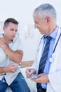 Doctor examining his patient and writing on clipboard Royalty Free Stock Photo