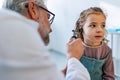 Doctor examining little girl's ear using otoscope, looking for infection. Friendly relationship between the doctor Royalty Free Stock Photo