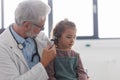 Doctor examining little girl& x27;s ear using otoscope, looking for infection. Friendly relationship between the doctor Royalty Free Stock Photo