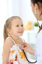 Doctor examining a little girl by stethoscope. Happy smiling child patient at usual medical inspection. Medicine and Royalty Free Stock Photo