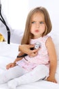 Doctor examining a little girl by stethoscope. Patient is in perplexity Royalty Free Stock Photo