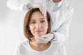 Doctor examining mature woman face before surgery on white background Royalty Free Stock Photo