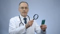 Doctor examining pack of pills with magnifying glass, counterfeit medication Royalty Free Stock Photo