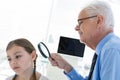Doctor examining patient ear by using magnifying glass Royalty Free Stock Photo
