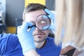 Doctor examining patients eye with magnifying glass closeup