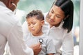 Doctor examining sad little boy by stethoscope. Sick boy crying while sitting with mother and male paediatrician listen Royalty Free Stock Photo