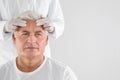 Doctor examining senior man face before cosmetic surgery on white background. Royalty Free Stock Photo